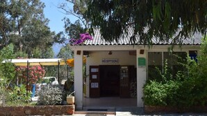 Zona de recepción con un cartel, vestíbulo cubierto y pared de piedra.