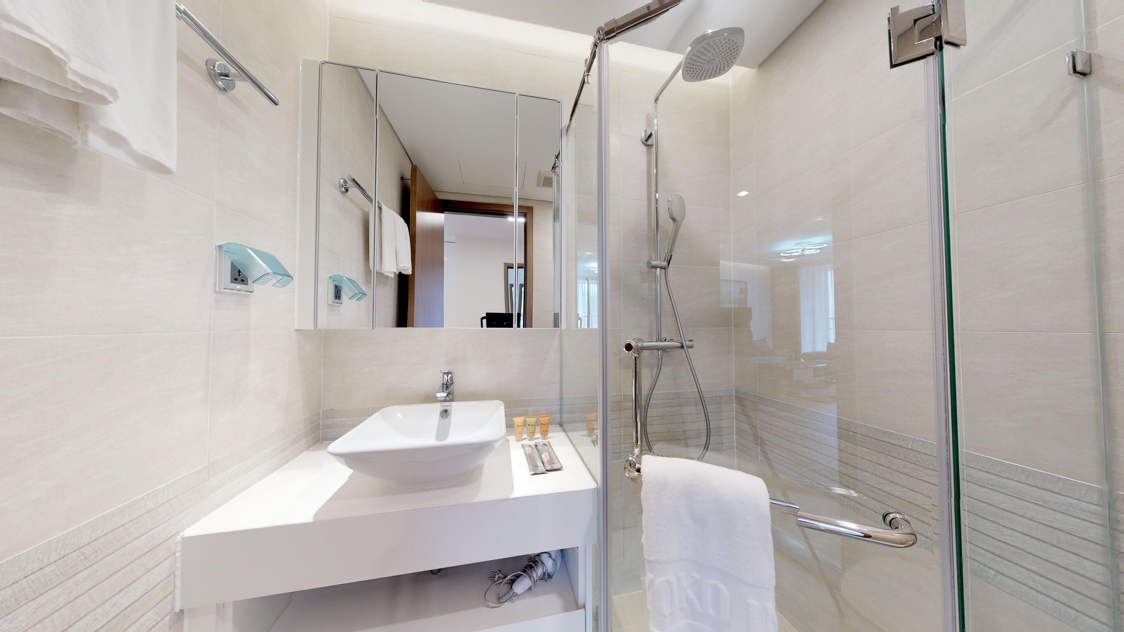 Un baño moderno con ducha acristalada, lavabo blanco y espejo.