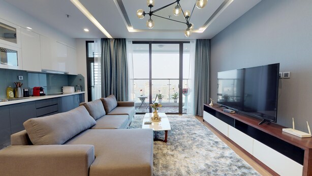 Een moderne woonkamer met een bank, een salontafel, een televisie en een balkon met planten.