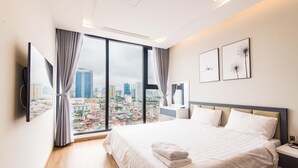 Een moderne hotelkamer met een groot bed, uitzicht over de stad en kunst aan de muur.
