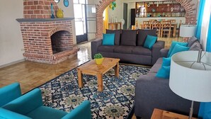 Una sala de estar con chimenea de ladrillo, un sofá, una mesita de centro y una alfombra estampada.