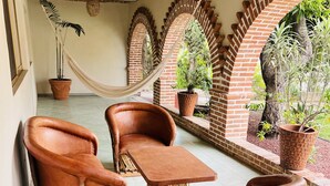 Un patio con arcos de ladrillo, mobiliario de terracota y plantas en macetas.
