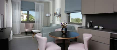 Una cocina moderna con armarios grises, una mesa redonda de comedor con sillas rosadas y un ventanal con cortinas.