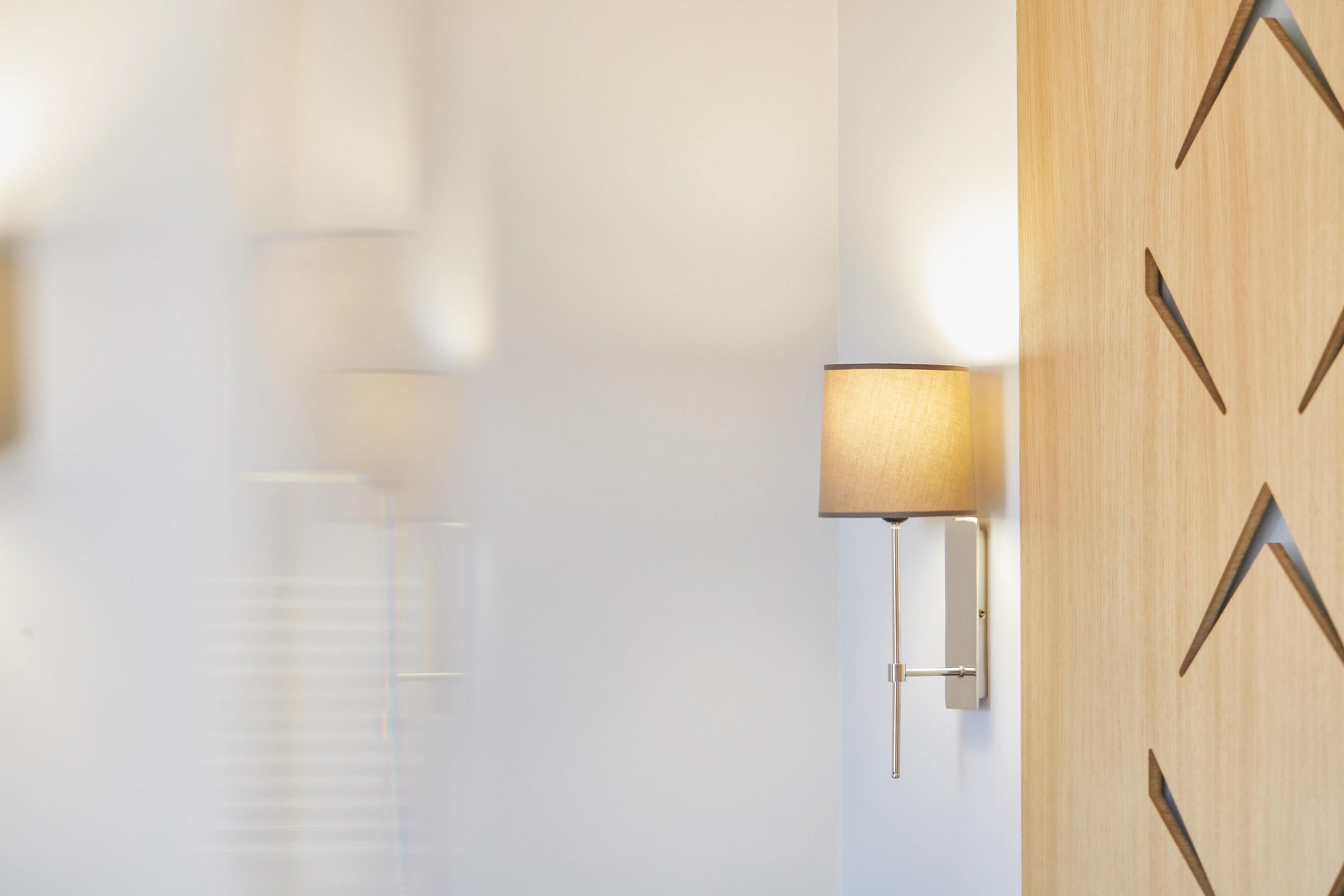 Un intérieur moderne avec une lampe fixée au mur et un lambris en bois aux motifs géométriques.