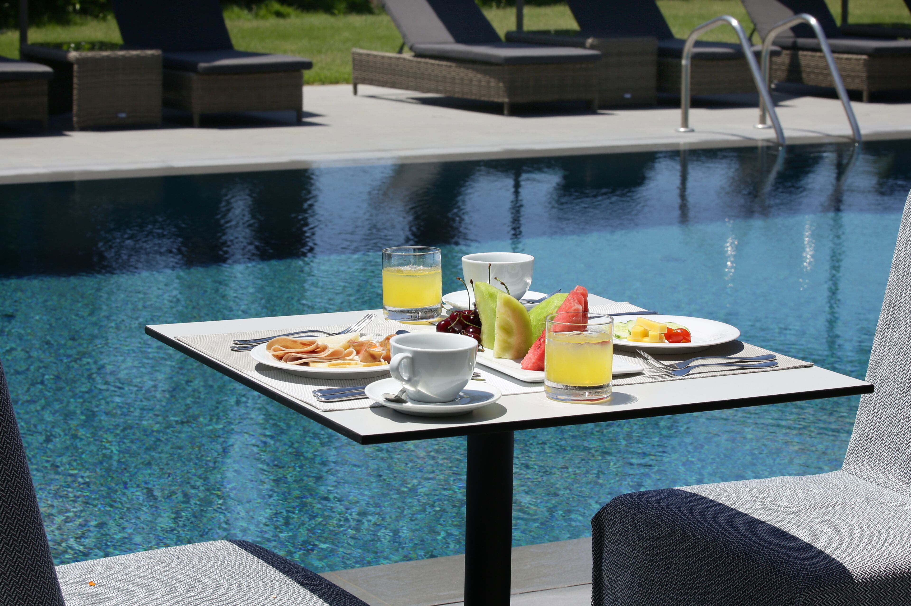 A dining table with breakfast items by a pool.