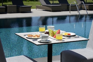 Ein Esstisch mit Frühstücksangeboten am Pool.