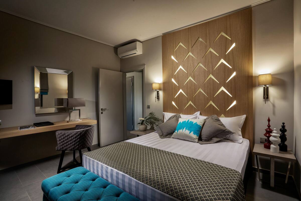 Ein modernes Hotelzimmer mit einem großen Bett, einem Schreibtisch, einem Stuhl und einem Nachttisch mit Lampe.