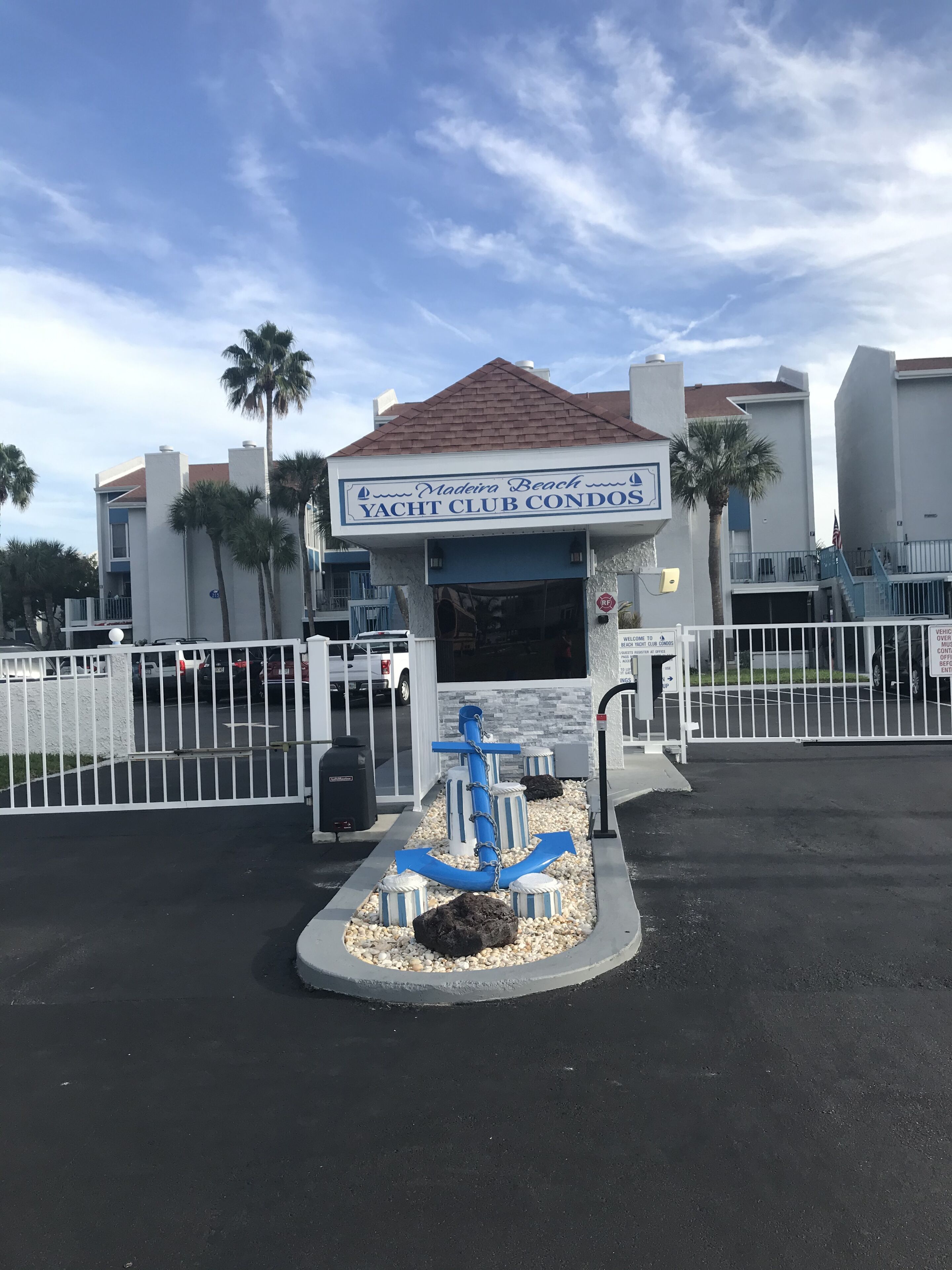 A yacht club with a sign, a gated entrance, and a decorative anchor.