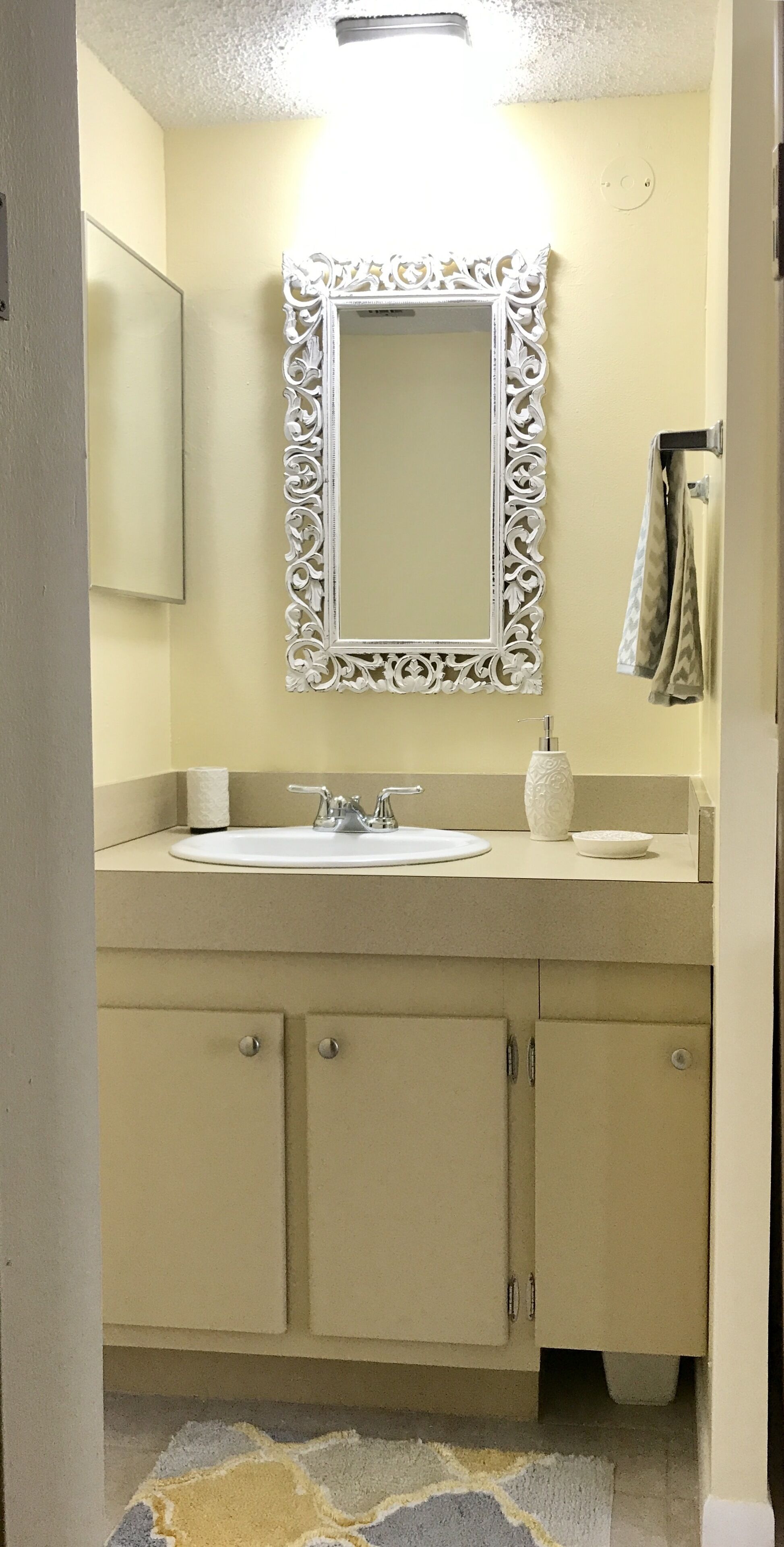 Un baño con lavamanos, espejo y muebles.