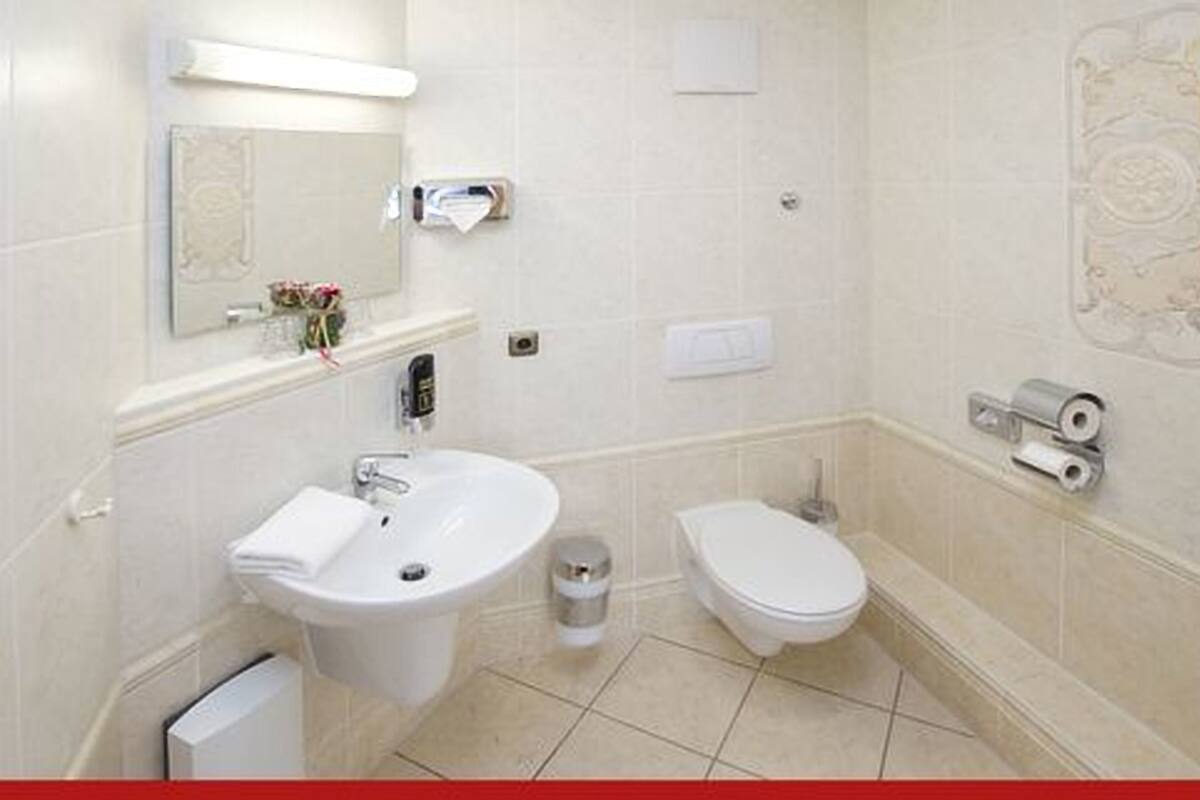 A bathroom with a sink, toilet, and a mirror.