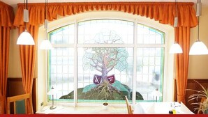 A room with a large arched window, curtains, and pendant lights. - Hotel & Restaurant zur Linde (Leuna)