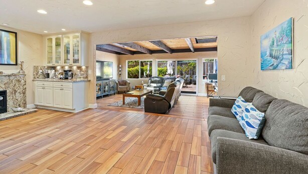 A spacious living area with a fireplace, a kitchen with a marble countertop, and a large window overlooking a garden. - Spacious Open Floor Plan (Santa Cruz)