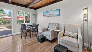 A room with a wooden ceiling, a dining table with chairs, two armchairs, a side table, a floor lamp, and a painting on the wall. - Spacious Open Floor Plan (Santa Cruz)