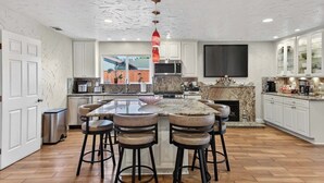 A modern kitchen with a central island, bar stools, a microwave, and a fireplace. - Spacious Open Floor Plan (Santa Cruz)