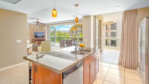 Eine moderne Küche mit einer großen Kochinsel, ein Essbereich mit Blick und ein Balkon mit Pool.