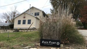 A sign for River Point at 22 E. Clinton Street, with a house in the background and a grassy area with a stone wall. - A perfect weekend gateway! (Grafton)