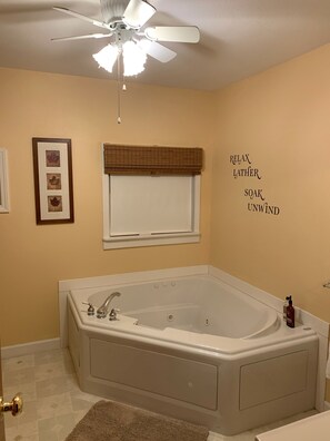 Een bad/douchecombinatie, een bubbelbad, een haardroger, handdoeken