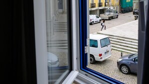 Una ventana con vista a una calle, con edificios y coches estacionados.