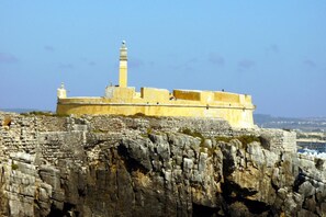 A historic building with a prominent tower, situated on rocky terrain with a clear view of the surrounding landscape.