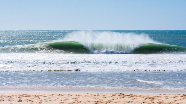 Una playa con olas y cielo despejado.