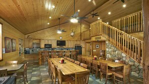 A spacious lodge with wooden interiors, a stone accent wall, and a dining area with multiple tables and chairs. - Gather Your Group at the Bunkhouse! (Port Washington)