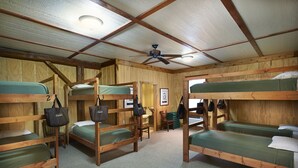 A cabin with bunk beds, a ceiling fan, and a framed picture on the wall. - Gather Your Group at the Bunkhouse! (Port Washington)
