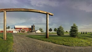 A rural farm entrance with a gravel path leading to a barn and silo. - Gather Your Group at the Bunkhouse! (Port Washington)