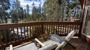 Eine Holzterrasse mit zwei Liegestühlen und einem Hollerdungszaun.