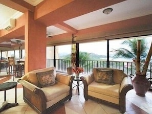 A spacious balcony with two leather sofas, a small table, and a large vase with flowers. - Million Dollar View in Heart of Flamingo w/Costa Rican Decor! (Guanacaste)