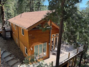Une cabane en bois avec un toit rouge, de grandes fenêtres et une terrasse.