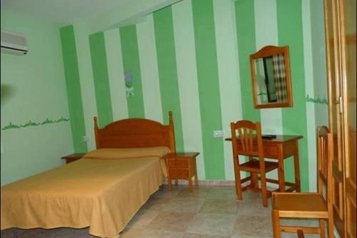 Una habitación con cama, una silla y un escritorio.