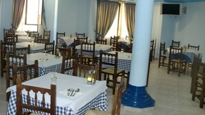 Un comedor con varias mesas y sillas, cada conjunto con manteles blancos y caminos de mesa a cuadros azules y blancos.
