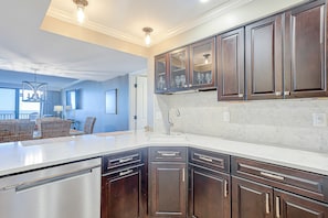 Enjoy meals in this kitchen with an oven, stainless steel appliances, and a dining area with wicker furniture.
