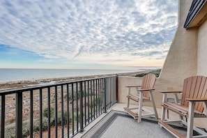 Enjoy the ocean view from this balcony with a rug and two Adirondack chairs.