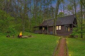 Une cabane dotée d’une terrasse, entourée d’une forêt.