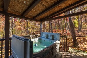 Un bain à remous dans un gazebo en bois, avec vue sur la forêt.