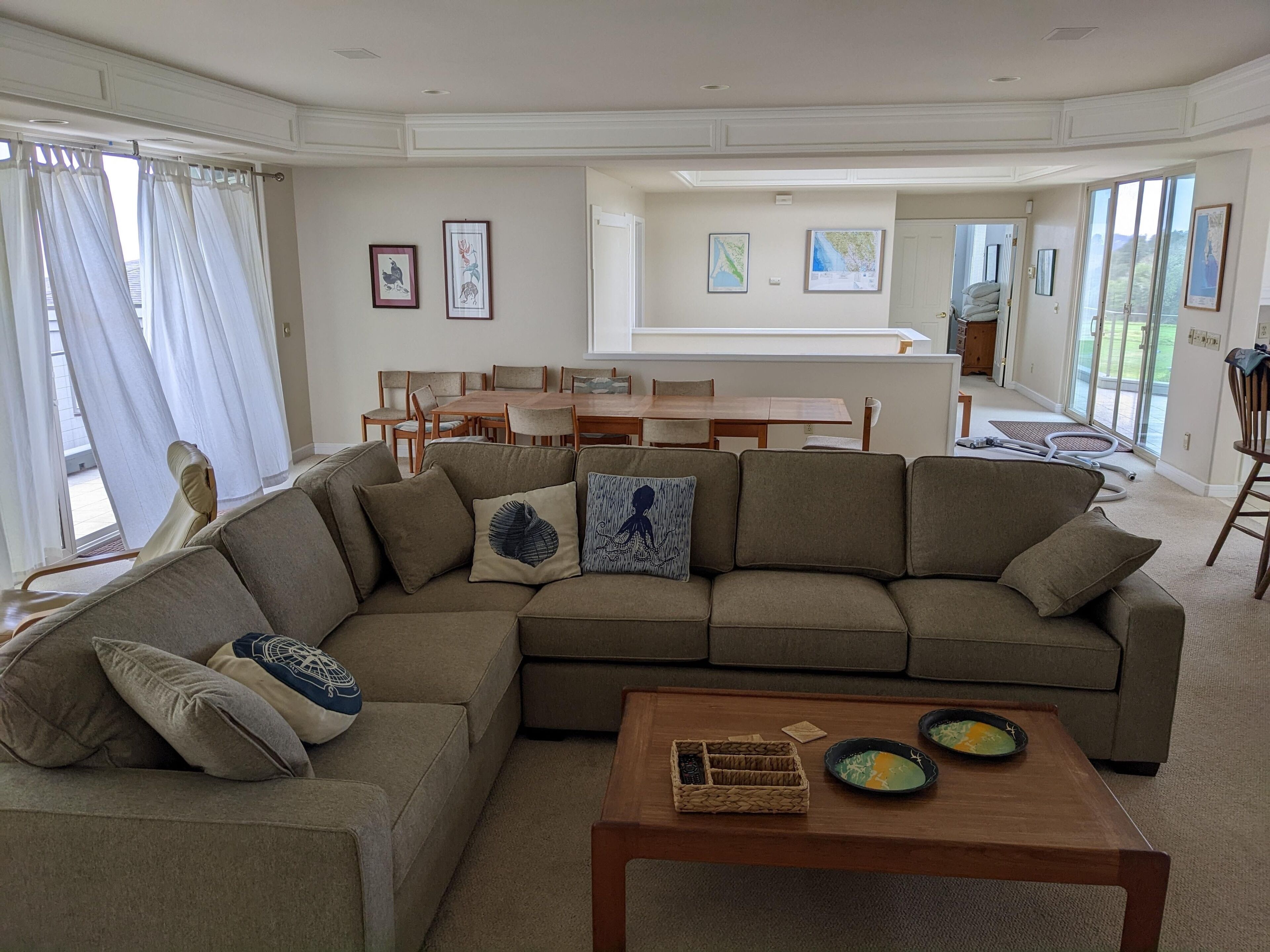 A modern living room with a sectional sofa, a wooden coffee table, and a dining area with a table and chairs.