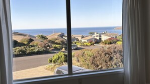 A view from a window overlooking a residential area with houses, a road, and the ocean. - Spacious 5-bedrm home:Ocean Views,hot tub,BBQ,pool & ping pong tables, fast wifi (Bodega Bay)