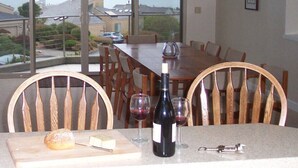 A dining area with a table set for two, a bottle of wine, and a dessert on a cutting board. - Spacious 5-bedrm home:Ocean Views,hot tub,BBQ,pool & ping pong tables, fast wifi (Bodega Bay)