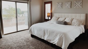 A bedroom with a large bed, a ceiling fan, a window with curtains, and decorative wall art. - Resort-Style Oasis | Pool & Spa | Waterslide | Basketball Court (Gilbert)