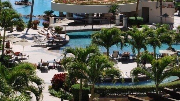 A resort with multiple swimming pools, palm trees, and a view of the ocean and cruise ships in the background. - Everything you need! Ocean views from your balcony! (Cabo San Lucas)