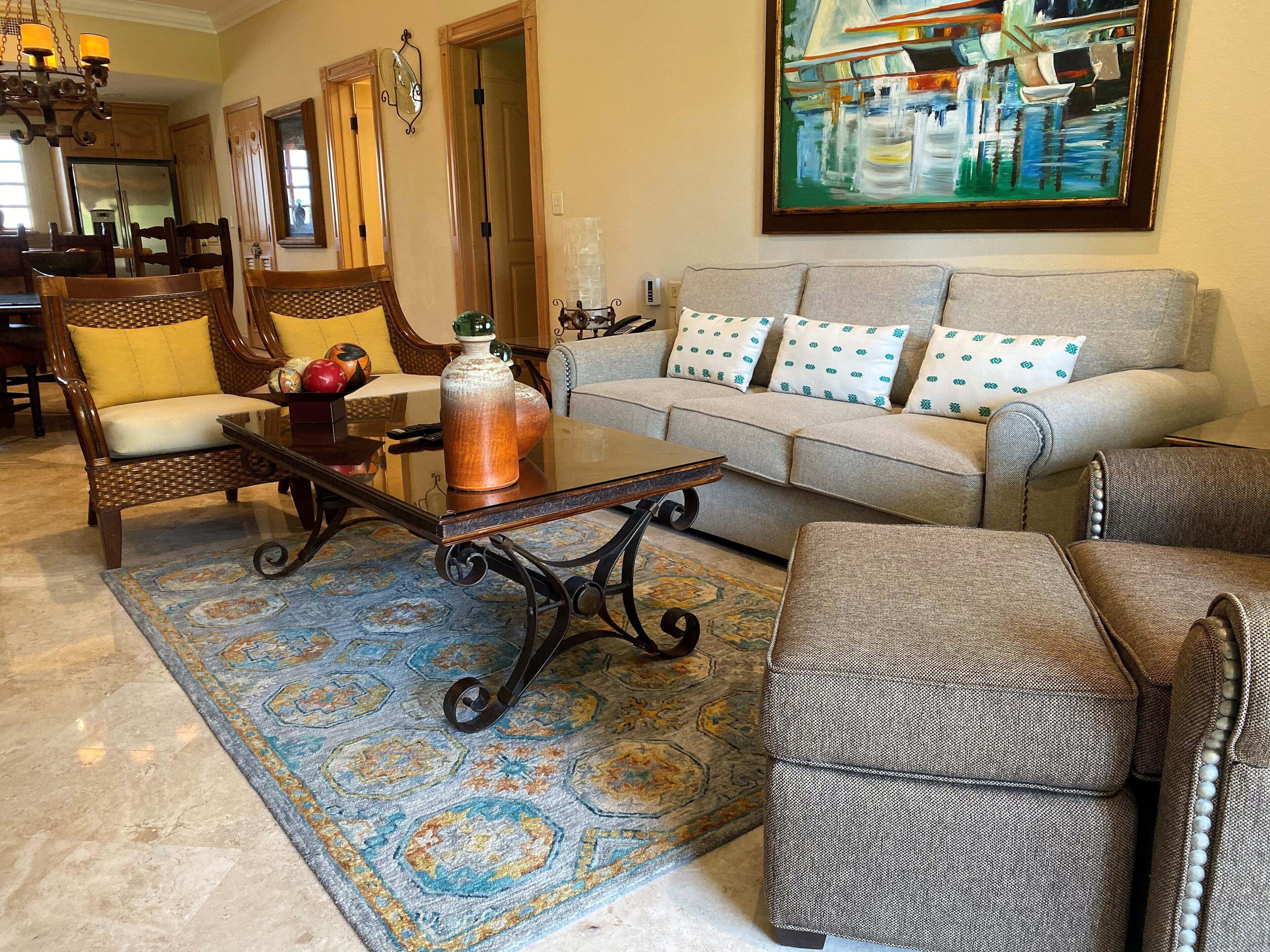 A living room with a sofa, armchairs, a coffee table, and a rug.