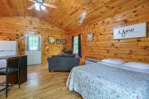 A cabin interior with a bed, a sofa, a desk, and a ceiling fan.