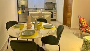 Une cuisine compacte dotée d’un îlot central, d’une table à manger avec des chaises et d’une petite table ronde avec un siège.