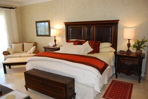 A hotel room with a large bed, a sofa, a wooden nightstand, and a red rug. - Pools * Hot Tubs * Swim-Up Bar * Spa * Pickleball * Medano Beach! (Cabo San Lucas)