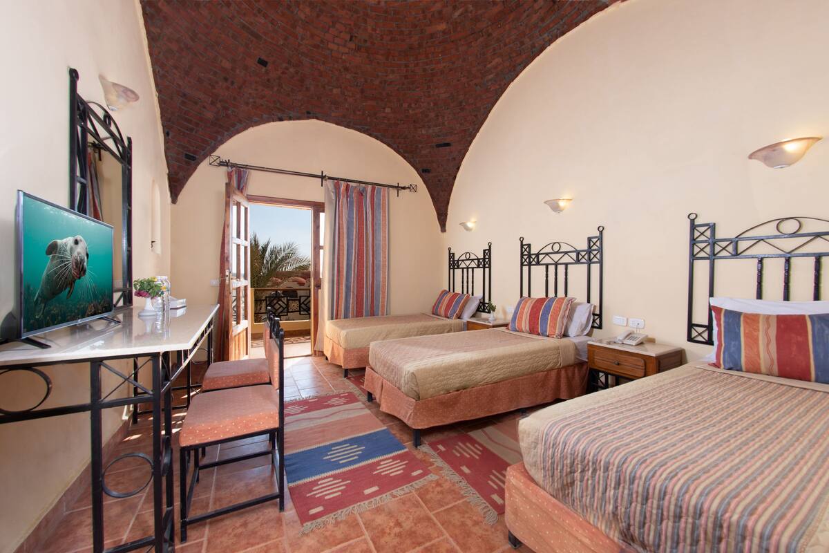Habitación de hotel con dos camas, un escritorio, una silla y un televisor.