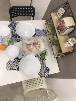 A dining table set with white plates, blue patterned napkins, and a clear plastic container with food. - centruMassimo (Palermo)