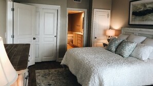 A bedroom with a bed, two nightstands, a lamp, a ceiling fan, and two doors leading to other rooms. - Prime October Dates Are Open! Perfect Time For a Beach Trip! (Orange Beach)