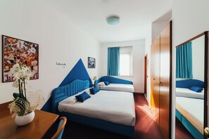A hotel room with a bed, a desk, a chair, a potted plant, and a poster on the wall. - Arcangelo Roof Hotel (Rimini)