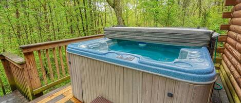 Un bain à remous sur une terrasse en bois, entouré d’une forêt.